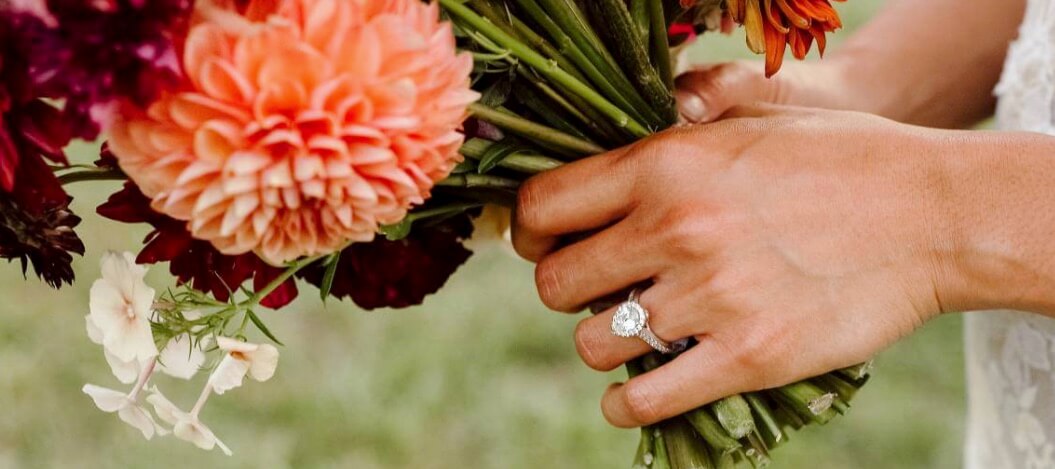 person wearing john atencio ring holding flowers